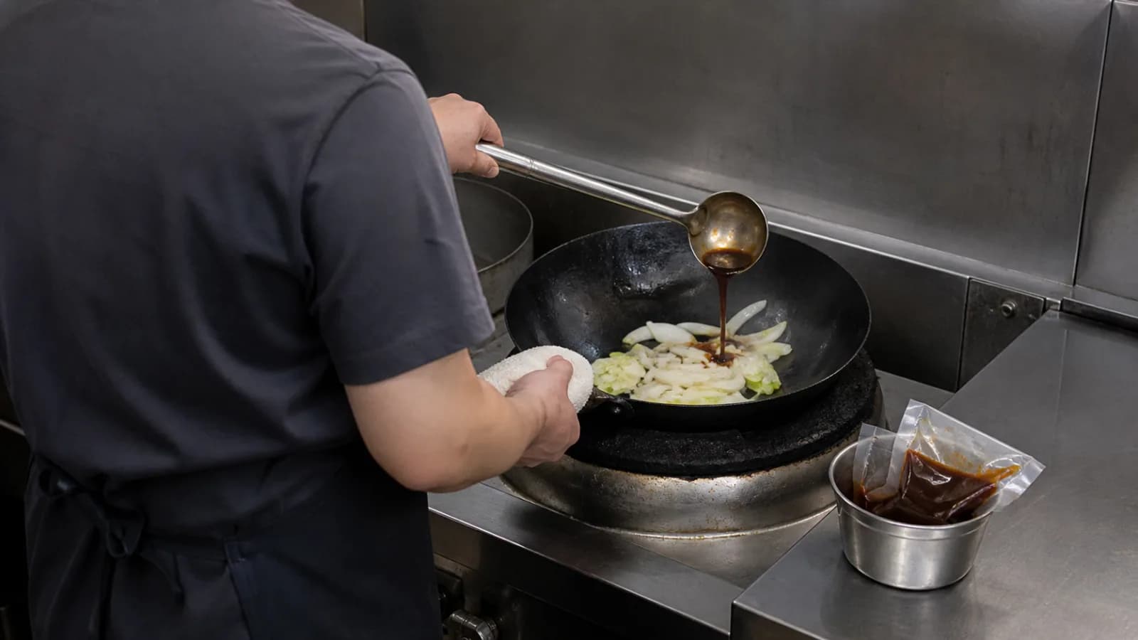 중식당 주방에서 소스를 국자로 덜어 웍의 채소에 넣는 초보 점주