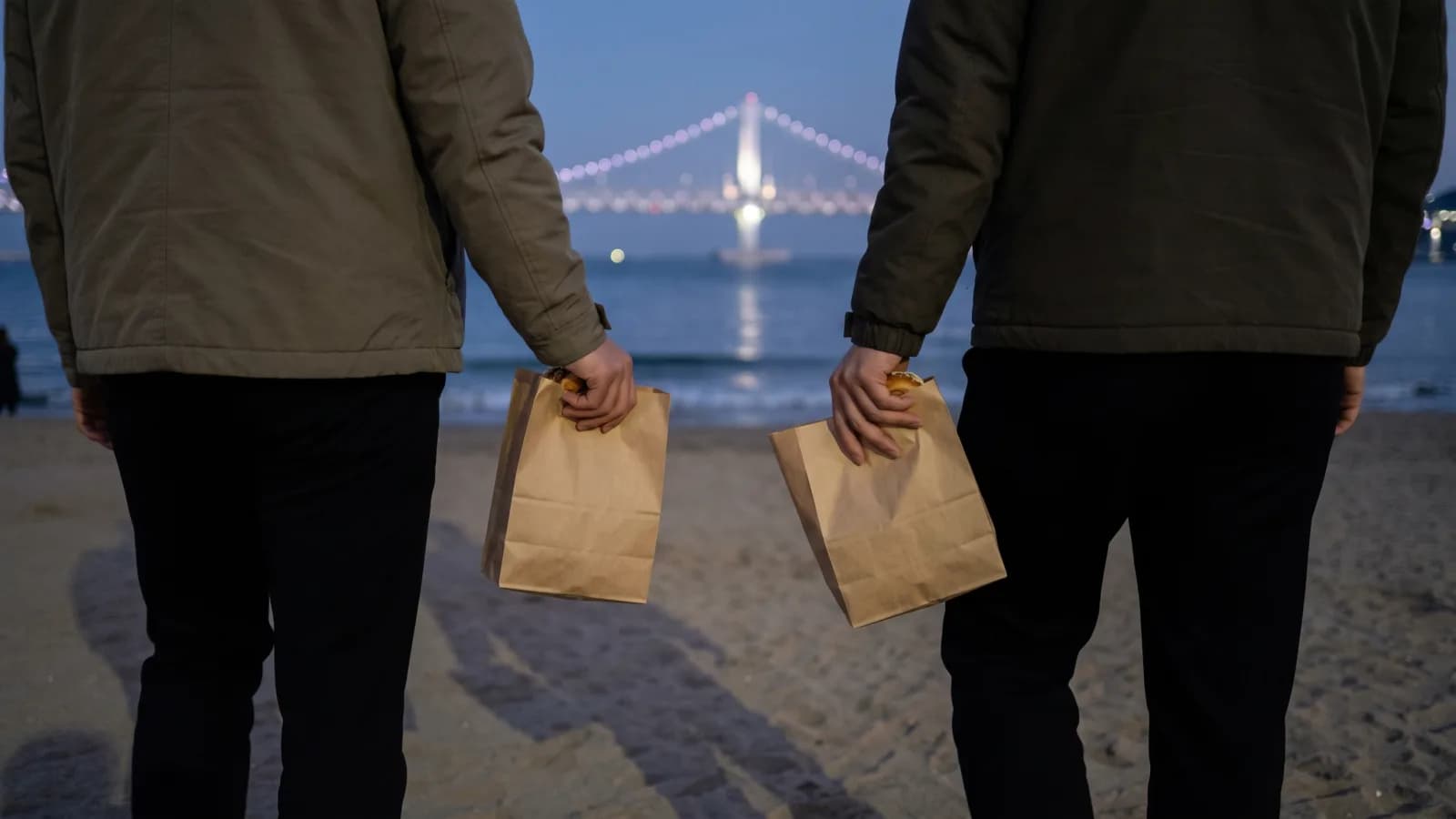 광안리 해변에서 종이봉투에 담긴 버거를 들고 이동하는 두 손님